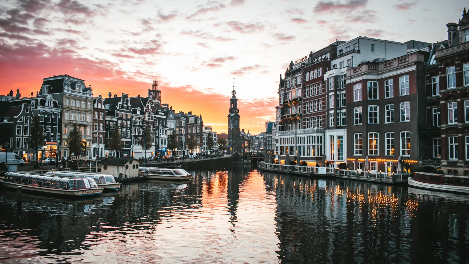 Canal de Ámsterdam al atardecer con casas tradicionales y botes